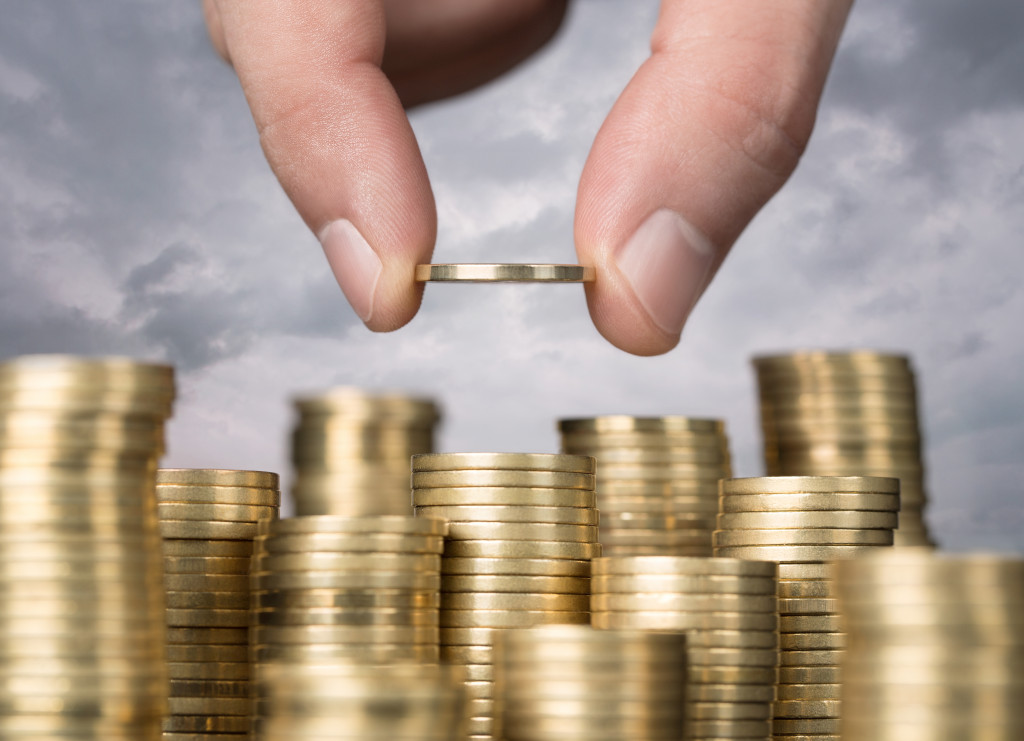 A hand putting a coin on top of a stack among others