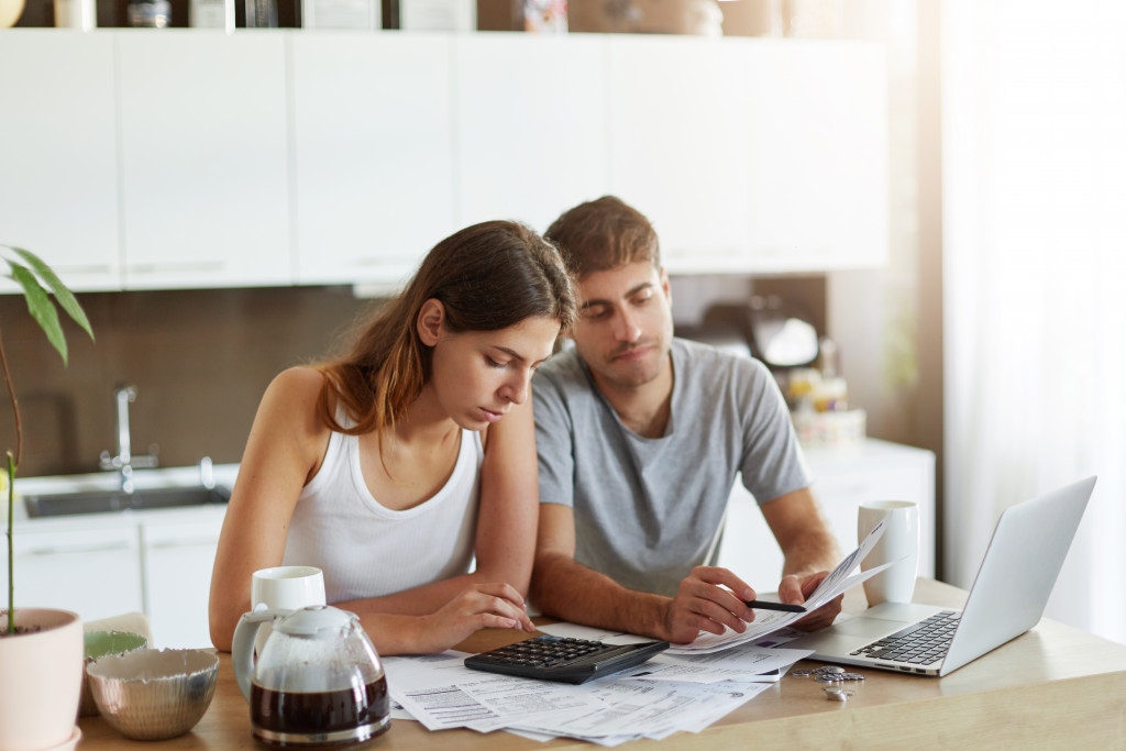 A married couple is seen at their kitchen table, looking over papers.