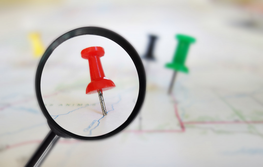 A magnifying glass over a red pin on a map