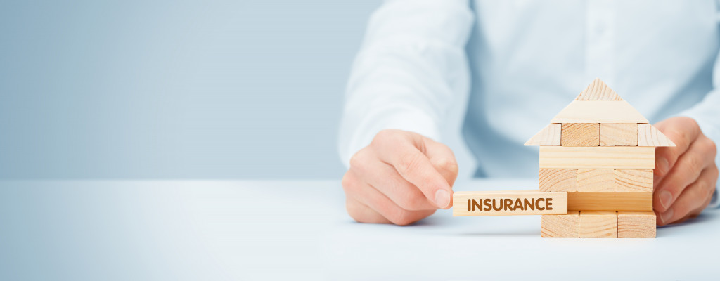 man adding jenga block with label house insurance to form home