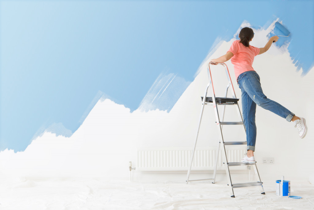 A woman on a ladder painting walls